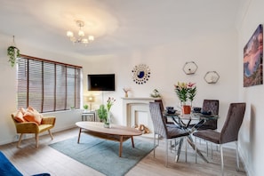 Relax in this stylish living room with a comfortable sofa, dining table, and fireplace.