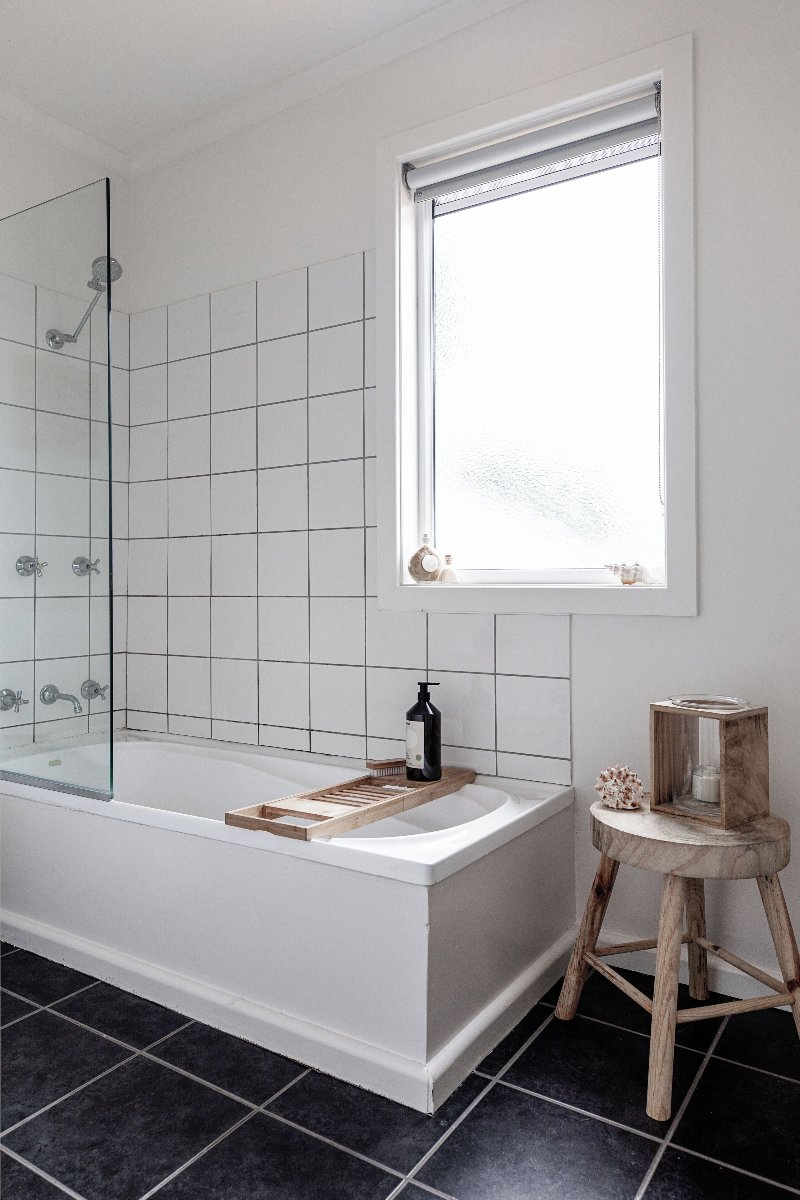 A modern bathroom with a glass-enclosed shower, a large bathtub, and a window providing natural light.
