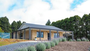 A modern house with a stone facade, large windows, and a covered porch.