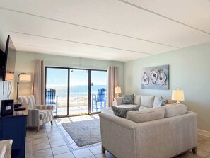 A living room with a sofa, chairs, a TV, and a painting. - Beachfront SGI Villa G3 Pool Sleeps 8 (St. George Island)