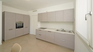 Una cocina moderna con armarios grises, horno integrado y pileta de acero inoxidable.