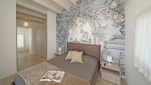 Un dormitorio con una cama grande, una mesita de noche y un papel tapiz floral en la pared.