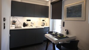 A modern kitchen with dark cabinets, a white countertop, and a dining area with a glass table.