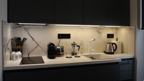 A modern kitchen with dark cabinets, a white countertop, and under-cabinet lighting.