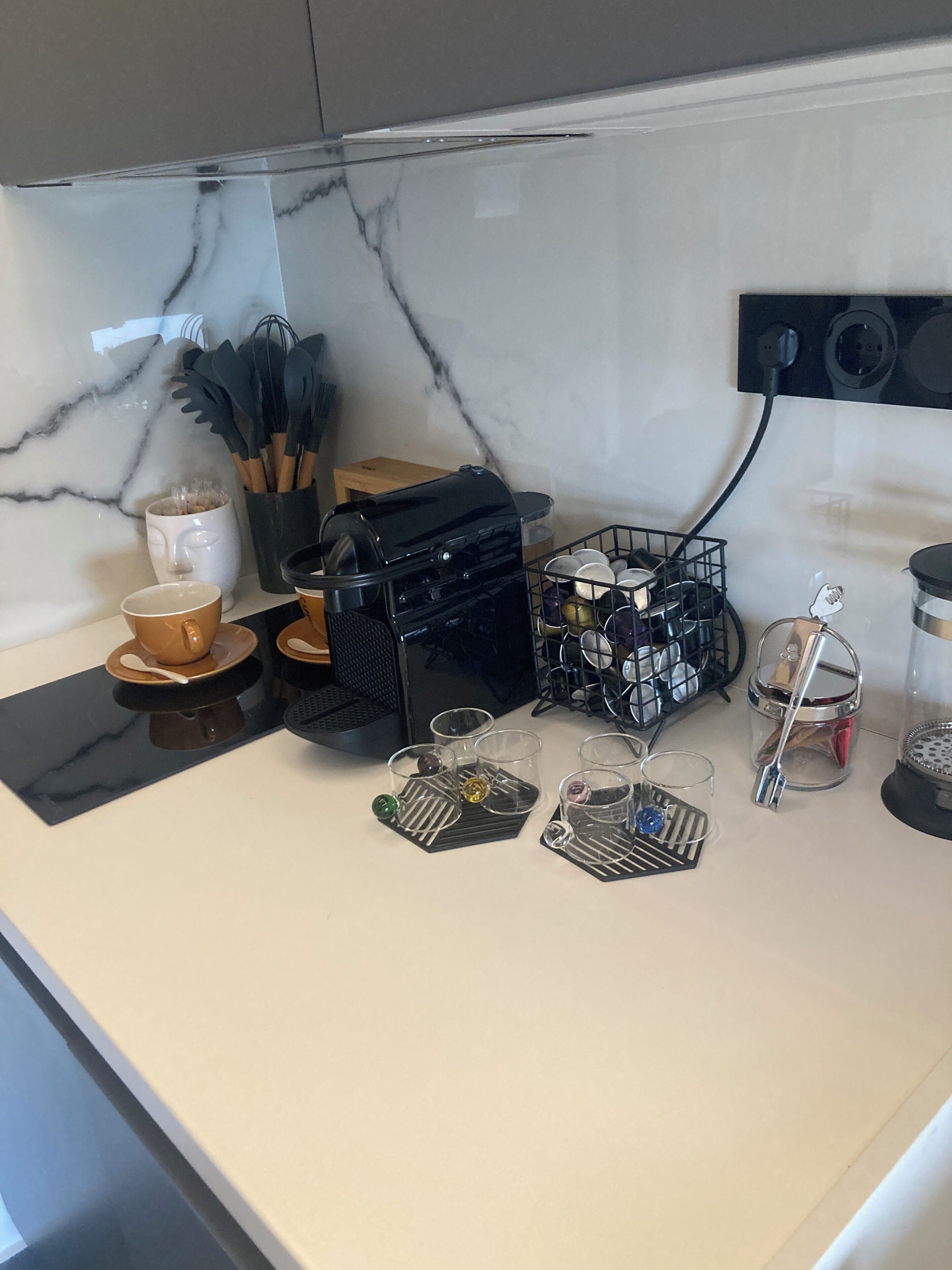 A kitchen counter with a coffee machine, a coffee cup, a mug, a spice rack, and a dish rack.