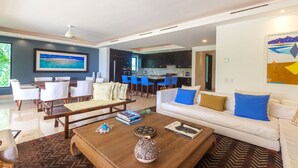 A modern living room with a dining area, a kitchen, and a view of the sea. - Perfect 4 Bedroom Condo (Punta de Mita)