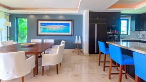 A modern kitchen with a large island, white chairs, and a dining table. - Perfect 4 Bedroom Condo (Punta de Mita)