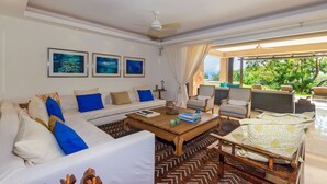 A living room with a sofa, armchairs, a coffee table, and a view of the outdoors. - Perfect 4 Bedroom Condo (Punta de Mita)