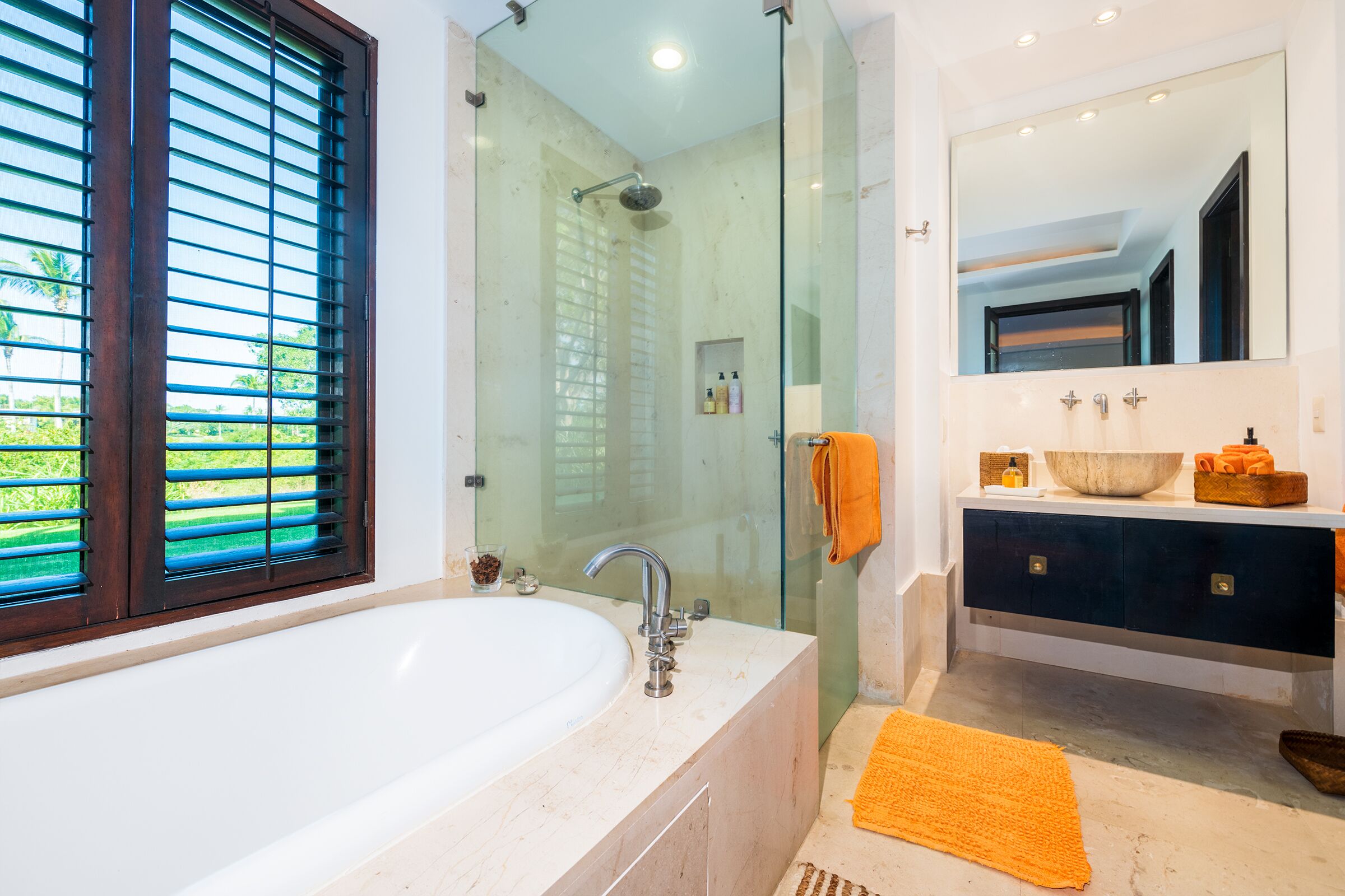 A modern bathroom with a glass-enclosed shower, a large bathtub, and a vanity with a mirror.