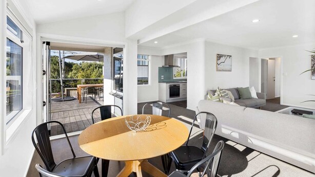 A modern apartment with a dining area, kitchen, and living room. - Mount Maunganui Beach House Family Friendly (Mount Maunganui)