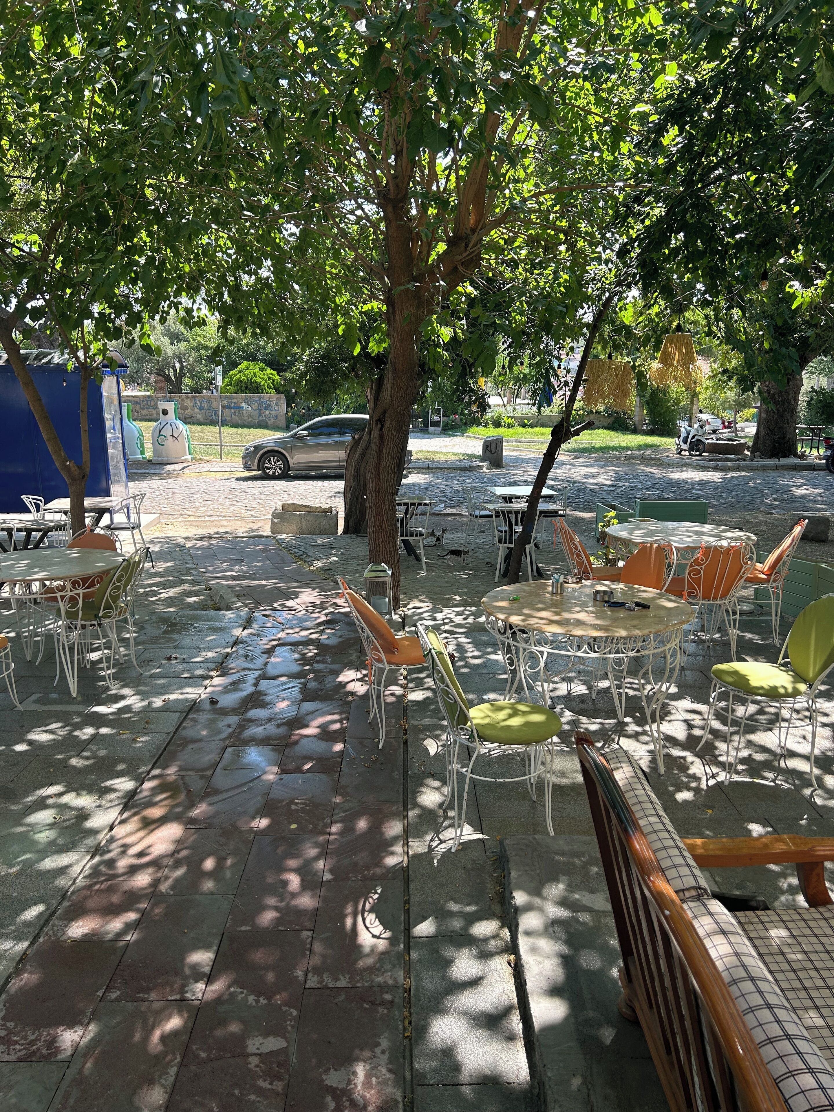 An outdoor seating area with tables and chairs, surrounded by trees.