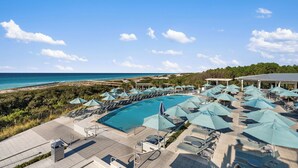 Ein Poolbereich eines Resorts mit Liegestühlen und Sonnenschirmen mit Blick auf einen Strand und den Ozean.