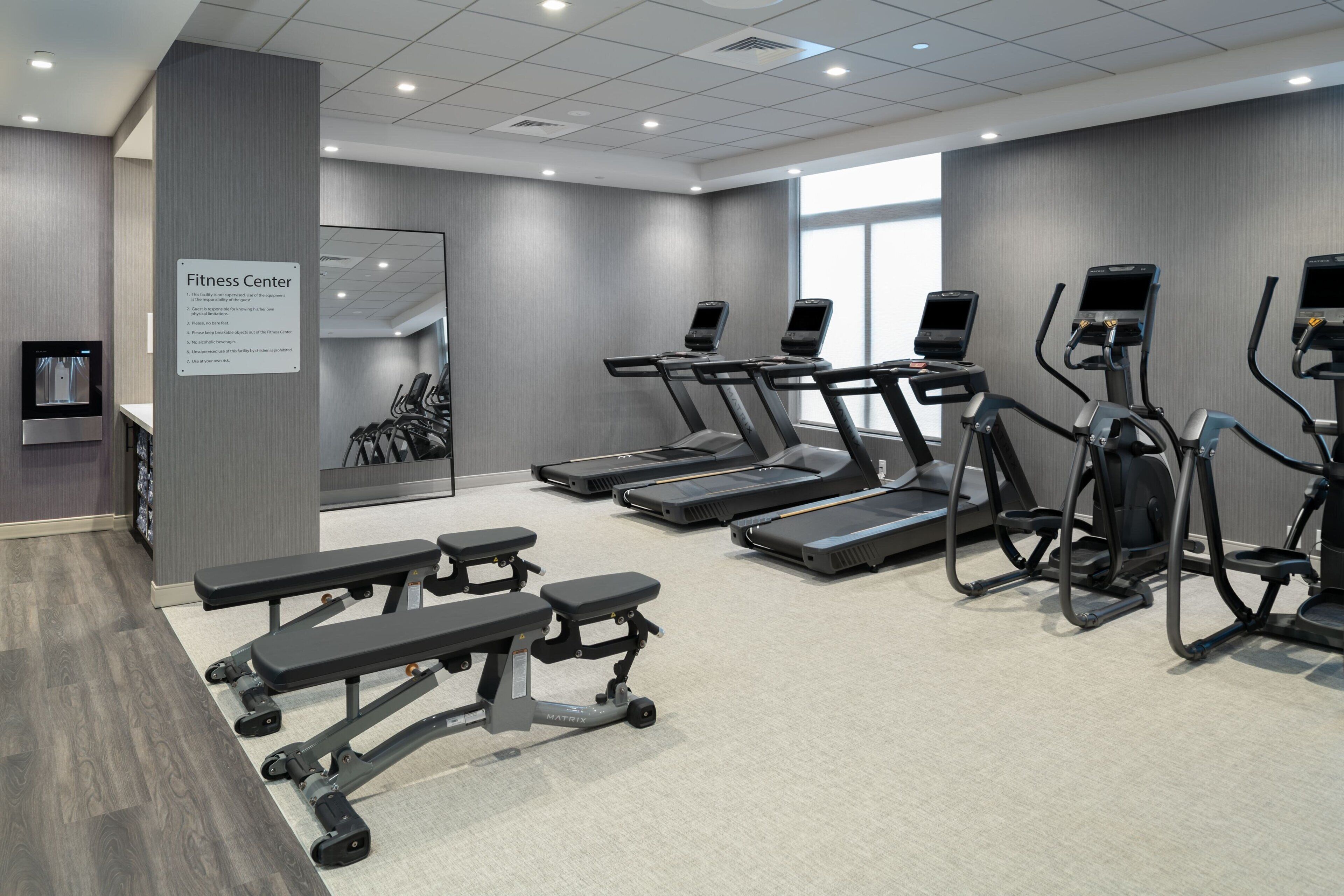 Un centre de remise en forme équipé de tapis de course, de vélos elliptiques et de bancs de musculation.