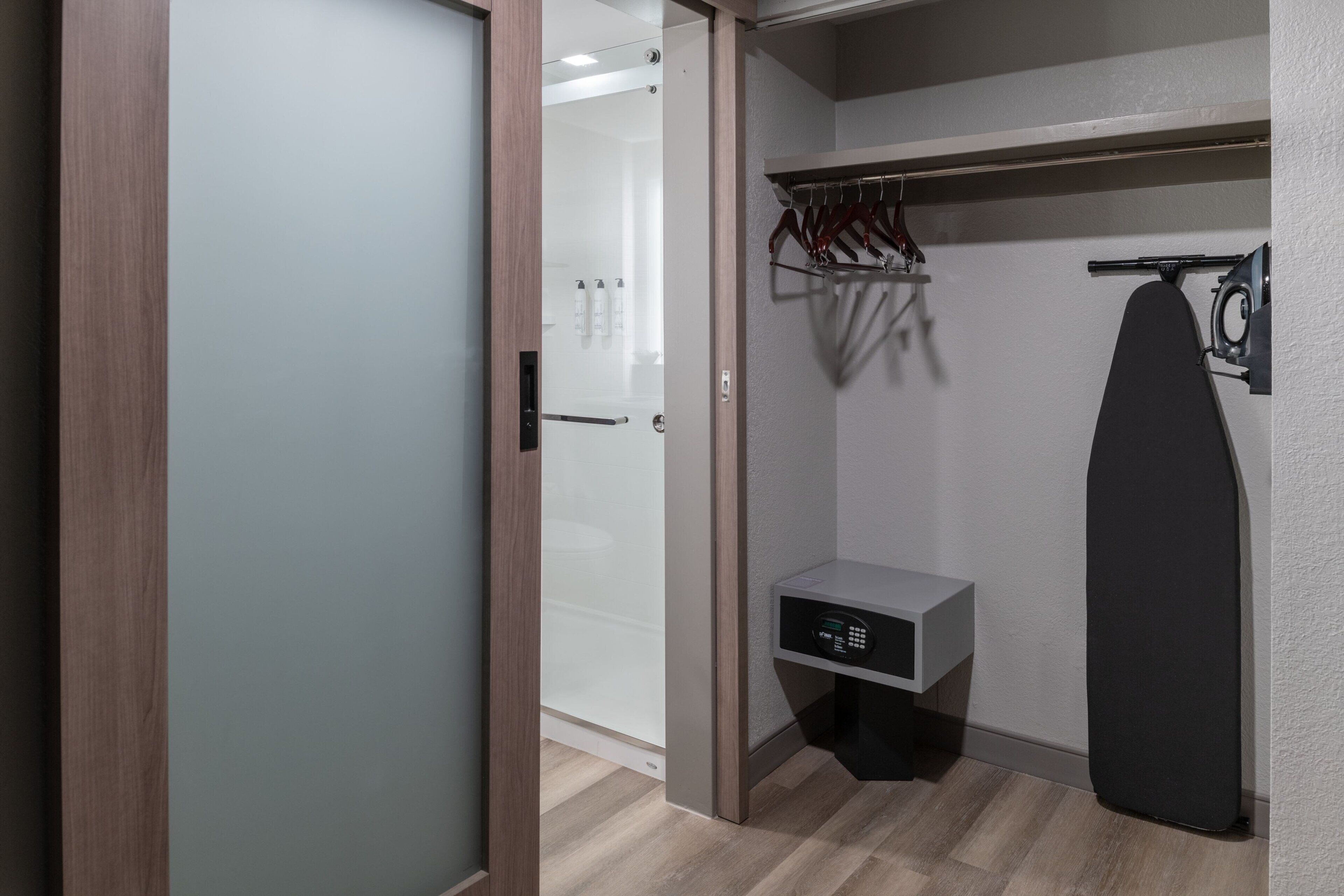 Un armario moderno con puerta corrediza, barra para colgar y un pequeño espacio de almacenamiento.