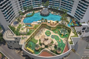 Un hôtel doté d’une piscine centrale, de nombreux balcons et d’un espace de jeux pour enfants.