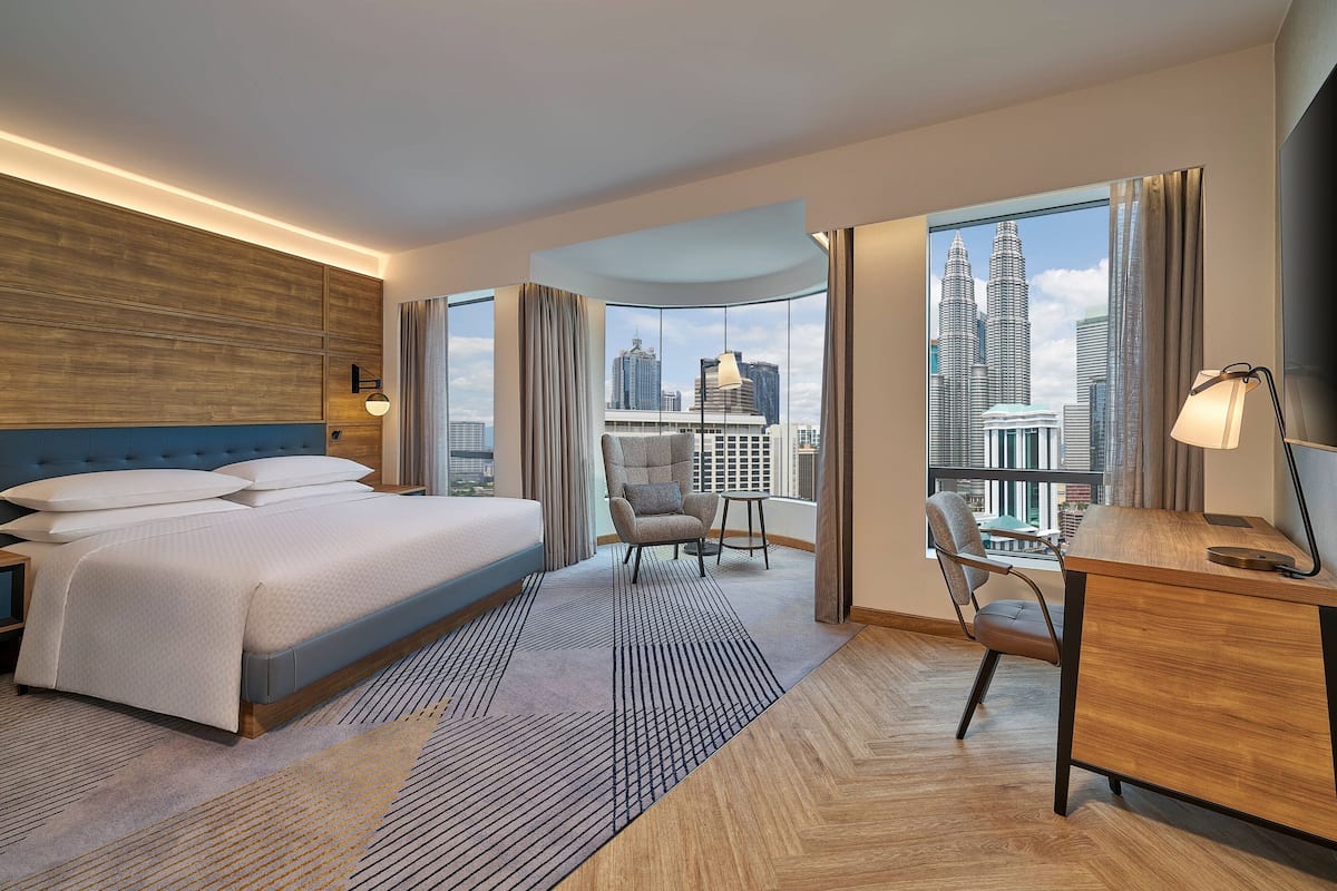 Een moderne hotelkamer met een groot bed, een bureau en uitzicht op de skyline van de stad.