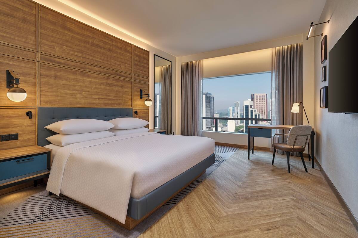 Een moderne hotelkamer met een groot bed, een bureau en uitzicht op de stadsbelangrijkste punten.