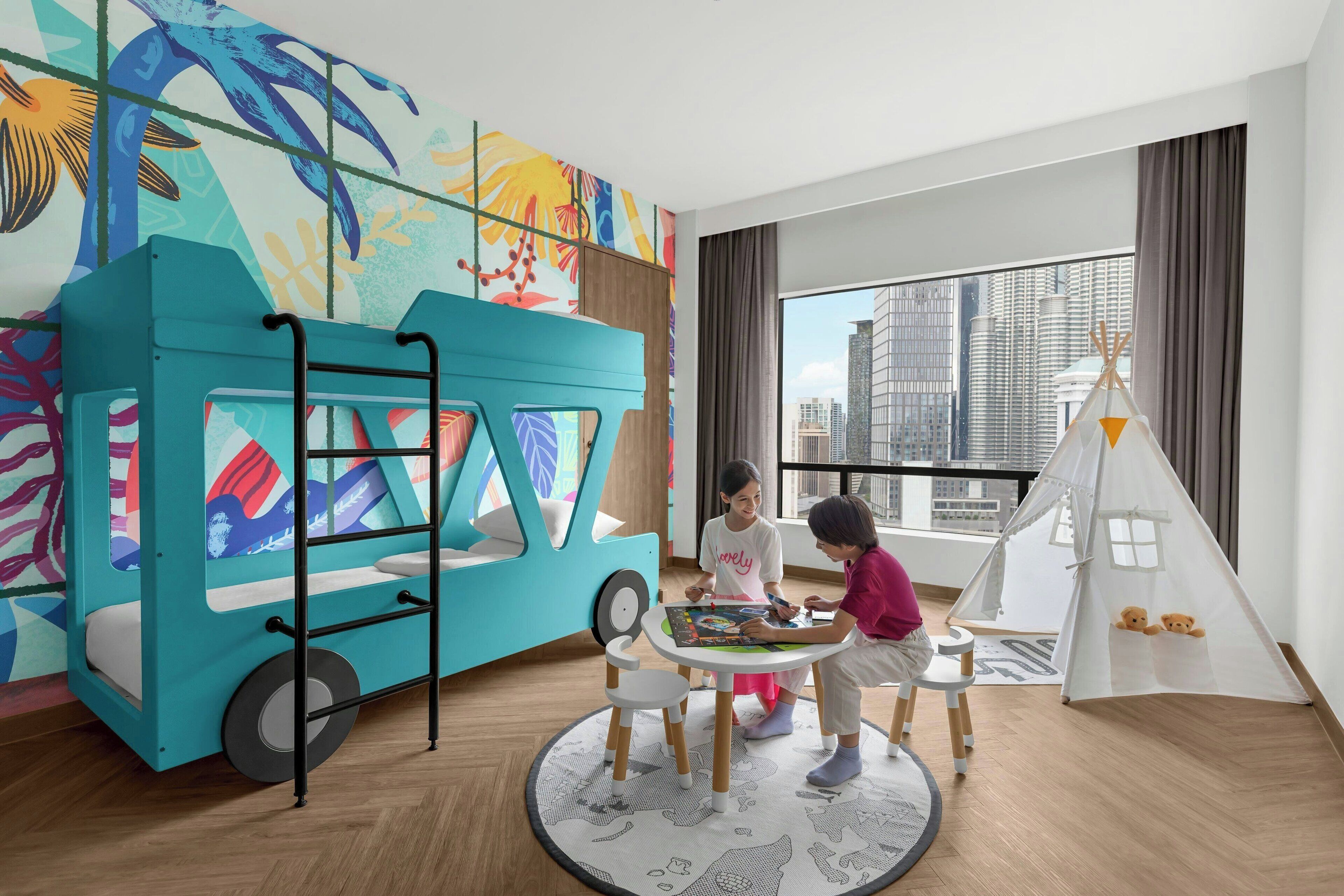 A children's play area with a colorful mural, a turquoise playhouse, and a white teepee.