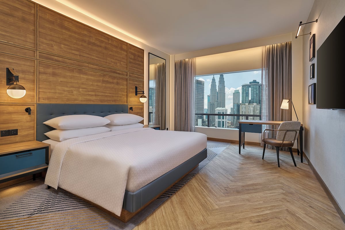 Hotelkamer met een groot bed, een bureau, een stoel, een televisie en uitzicht over de stad.