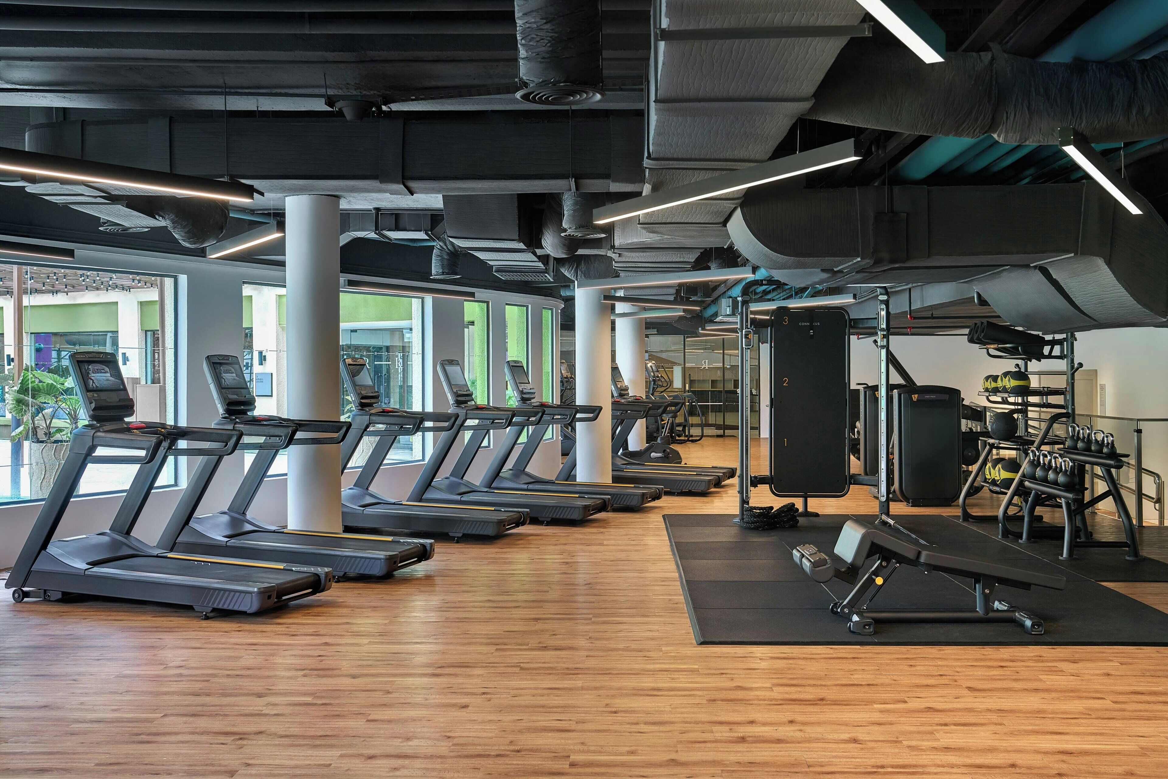 Une salle de sport équipée de tapis de course, d’appareils de musculation et de poids libres.