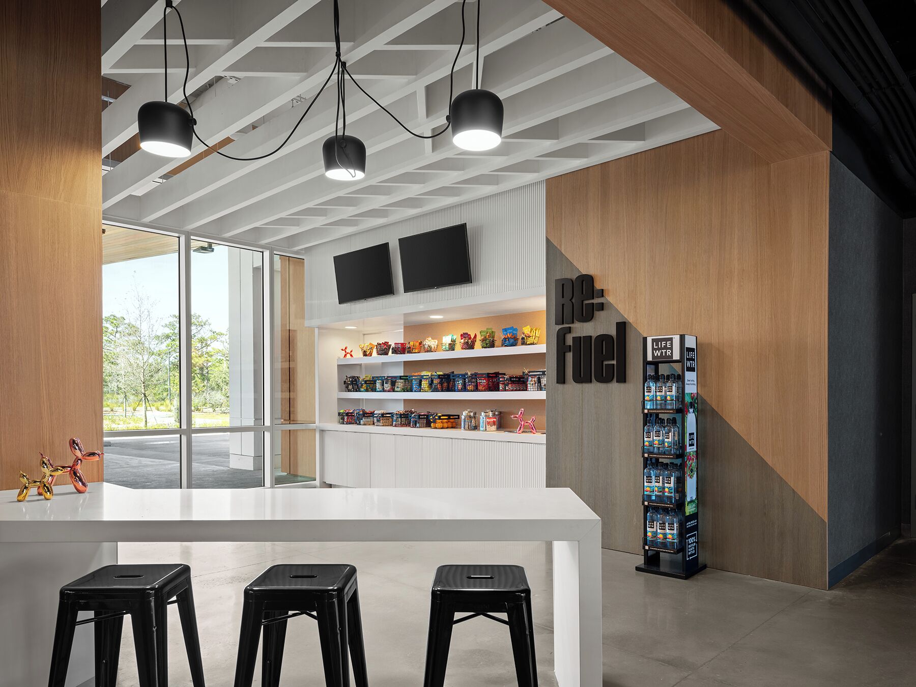 A modern bar area with a white counter, black stools, and a vending machine.