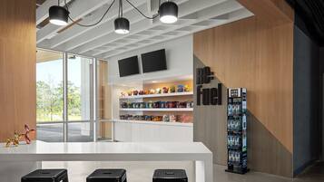 A modern bar area with a white counter, black stools, and a vending machine.