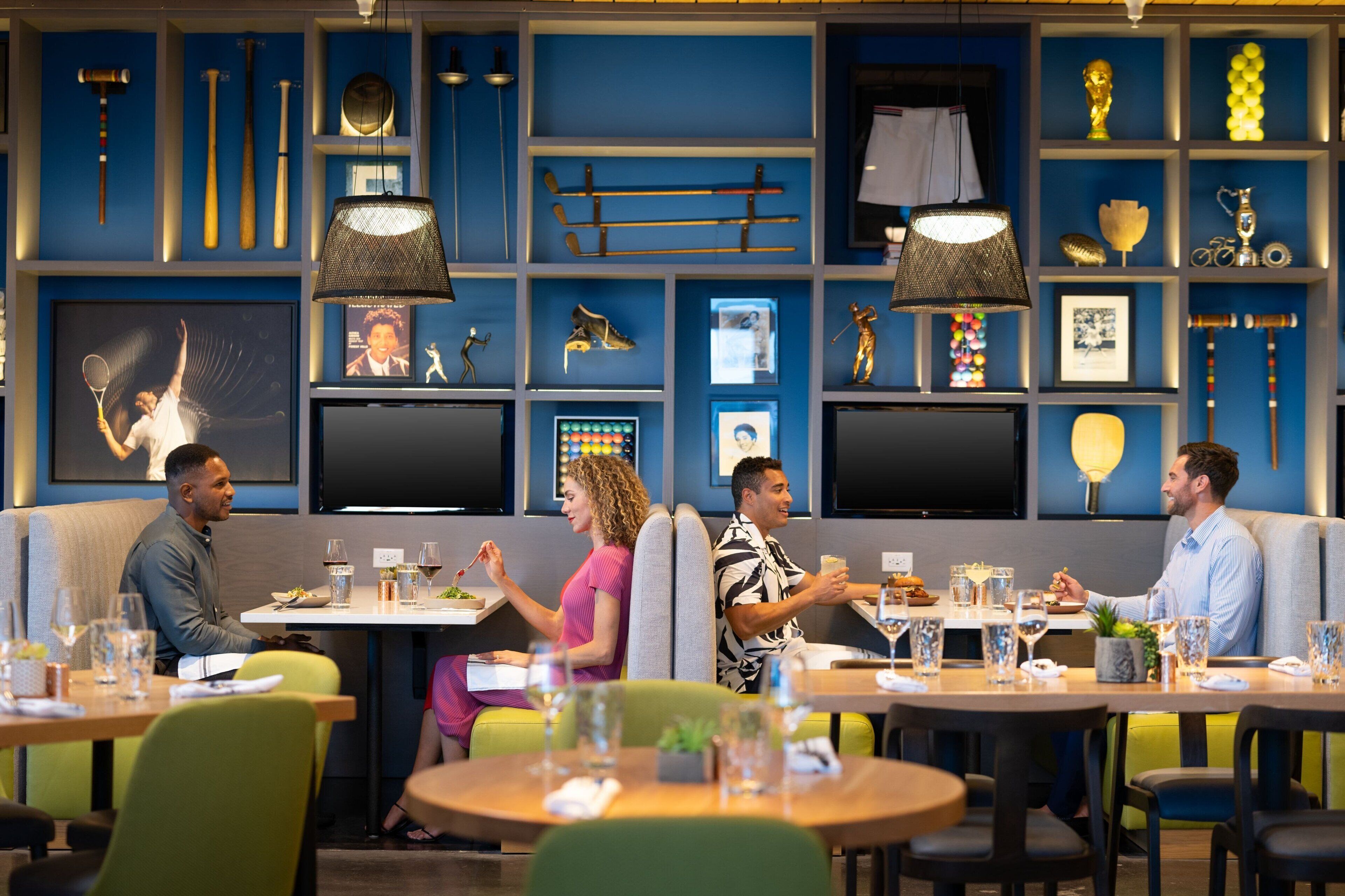 A restaurant with booths and round tables, blue walls, and various sports memorabilia.