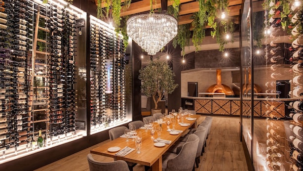 A restaurant with a long wooden table set for dining, surrounded by wine racks on both sides. - The Artisan At Tuscan Village, Salem, A Tribute Portfolio Hotel (Salem)