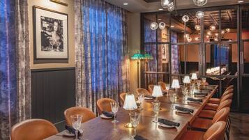 A long dining table with multiple chairs, lit by crystal chandeliers and table lamps.