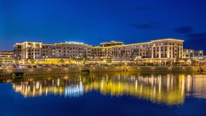 A multi-story hotel with a reflective pool in front, featuring a well-lit facade and a sign that reads "ARTISAN HOTEL." - The Artisan At Tuscan Village, Salem, A Tribute Portfolio Hotel (Salem)