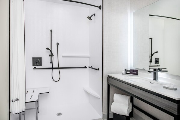 A modern bathroom with a shower, a sink, a mirror, and a towel rack.