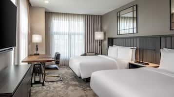 Una habitación de hotel con dos camas, un escritorio, una silla y un televisor.