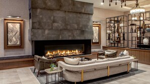 A modern living room with a fireplace, a sofa, and a coffee table. - The Artisan At Tuscan Village, Salem, A Tribute Portfolio Hotel (Salem)