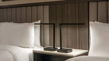 A hotel room with a wooden headboard, two bedside tables with black stands, and white bedding.
