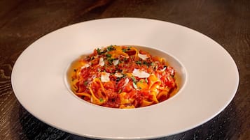 A white plate with pasta on a dark wooden table.