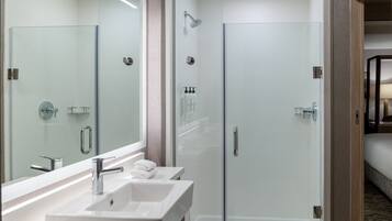 A modern bathroom with a glass shower enclosure, a double sink vanity, and a large mirror.