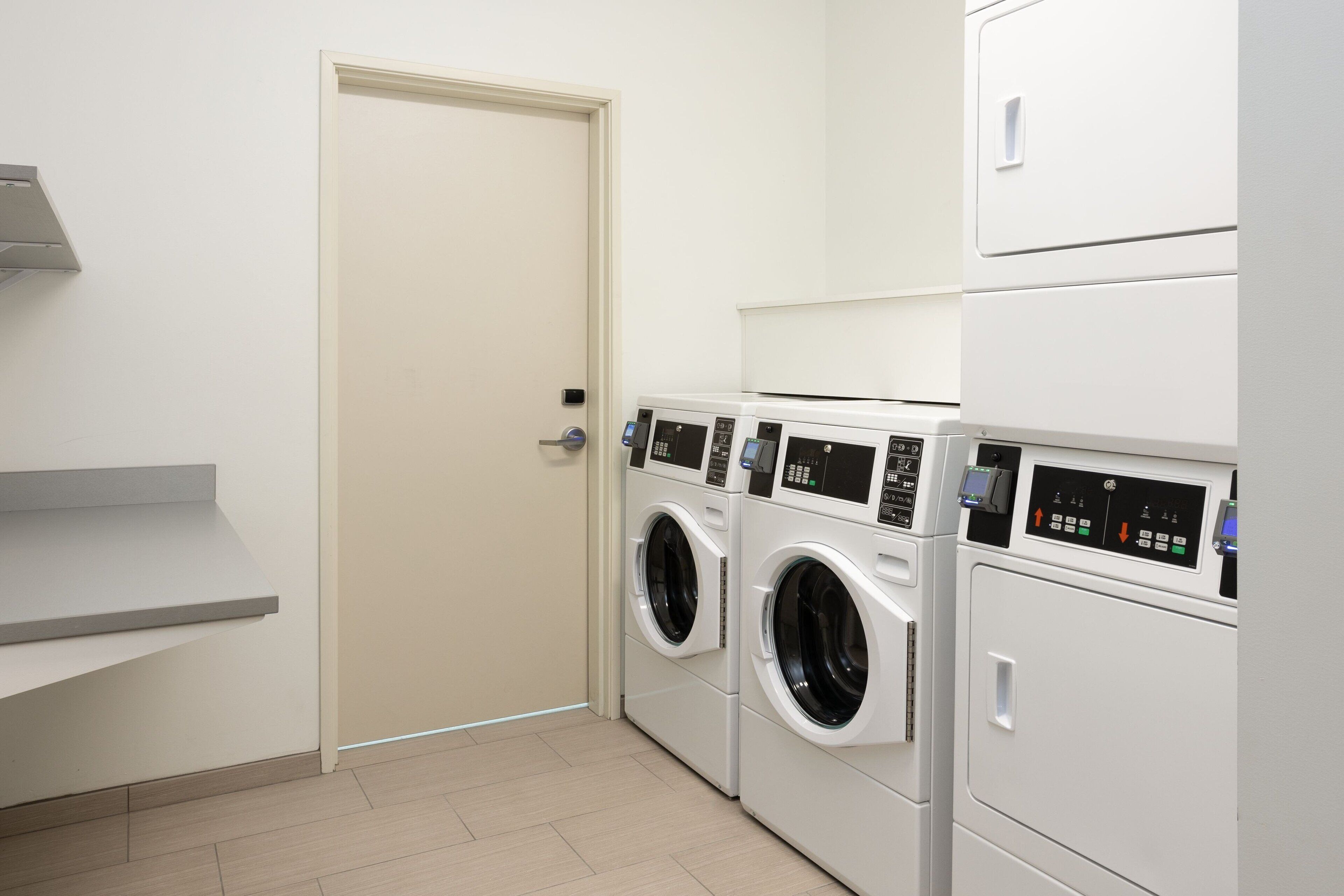 A laundry room with two front-loading washing machines and a stacked dryer.