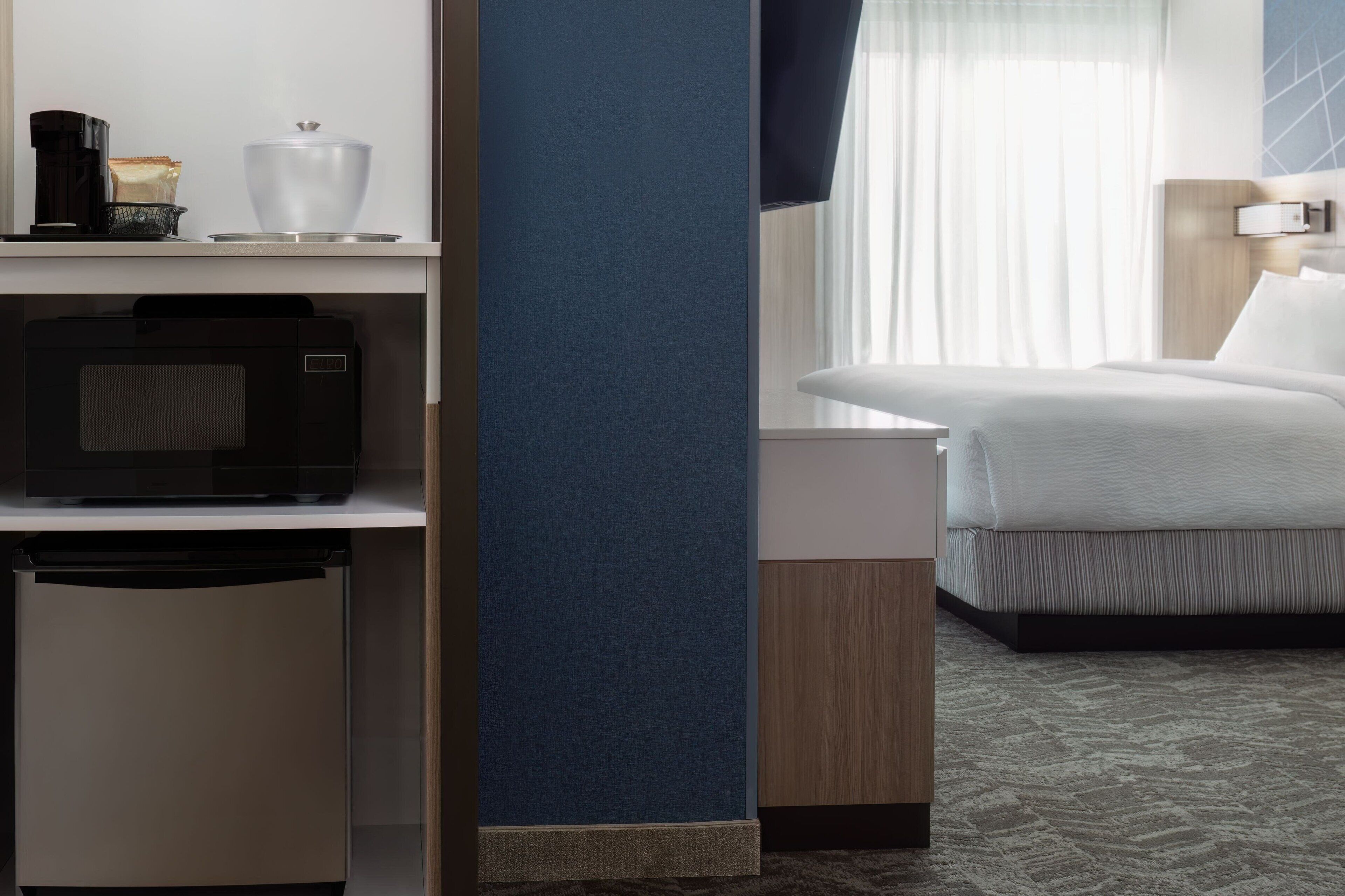 Une chambre d’hôtel équipée d’un lit, d’un four à micro-ondes, d’une machine à café et d’un petit réfrigérateur.