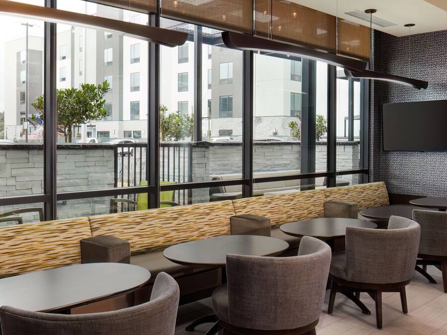 A modern lounge area with large windows, comfortable seating, and a flat-screen TV.