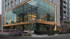 A modern building with a glass facade and a sign reading "Courtyard by Marriott." - Courtyard By Marriott Santo Domingo Piantini (Santo Domingo)