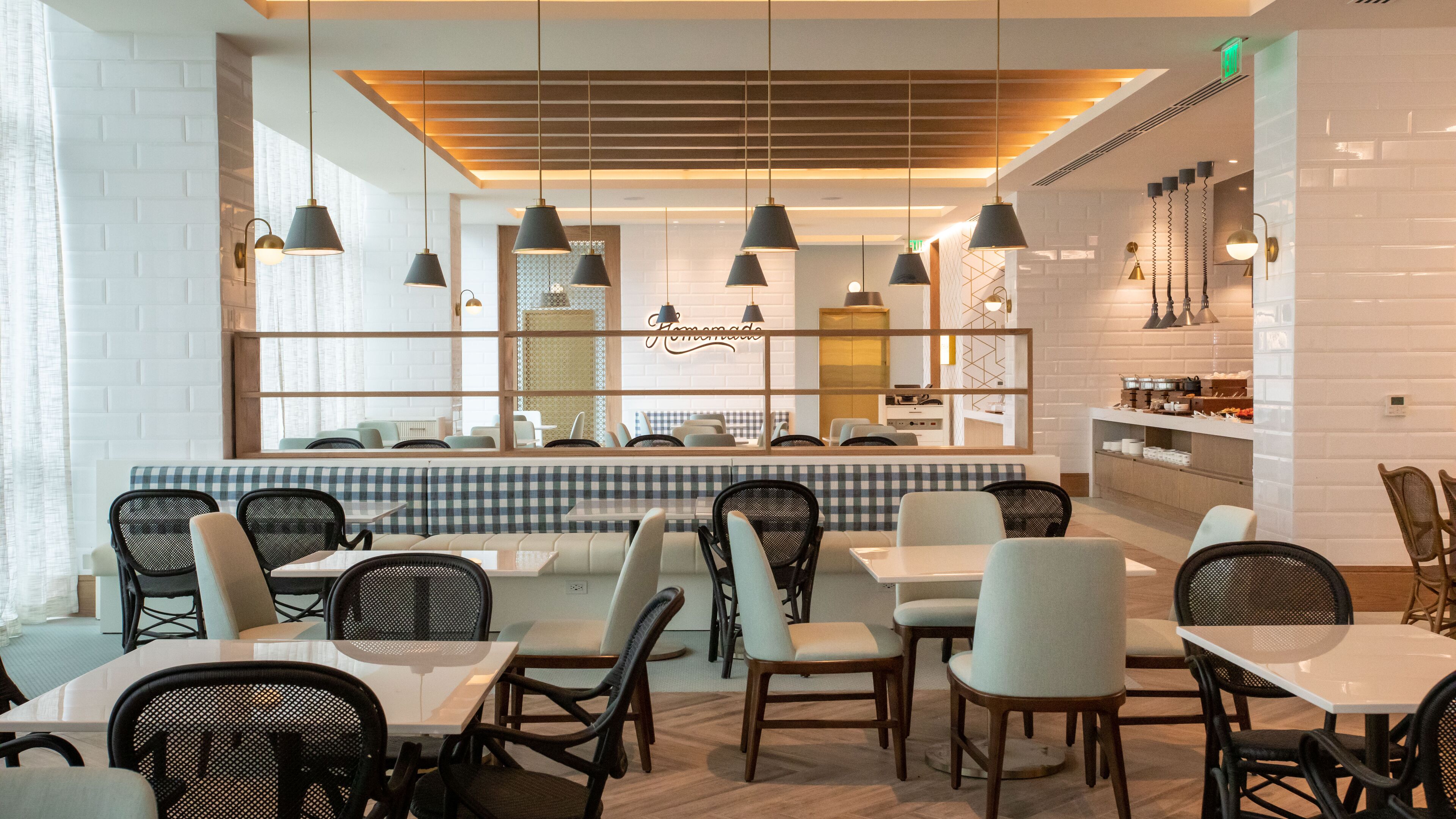 Interno di un ristorante moderno con sedute a cabina a scacchi, diversi tavoli e lampade a sospensione.