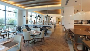 A modern restaurant with wooden flooring, black and white chairs, and pendant lighting. - Courtyard By Marriott Santo Domingo Piantini (Santo Domingo)