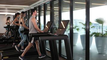 A gym with treadmills, large windows, and indoor plants.