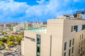Un edificio alto con un letrero que dice "COUTYARD" y vista de un paisaje urbano con varios edificios y cielo despejado.