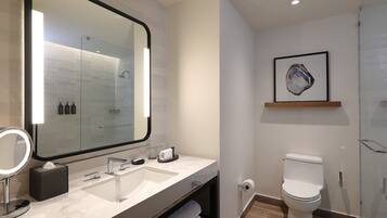 Un baño moderno con un espejo grande, dos lavamanos, un inodoro y una cabina de ducha de cristal.