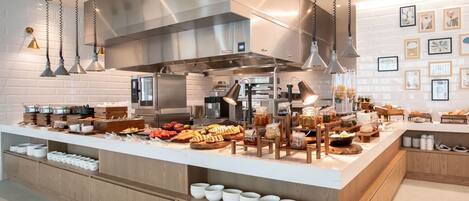A modern kitchen with stainless steel appliances, wooden countertops, and a variety of food items displayed.