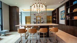 Un comedor moderno con una mesa central, cuatro taburetes de bar y una lámpara decorativa.