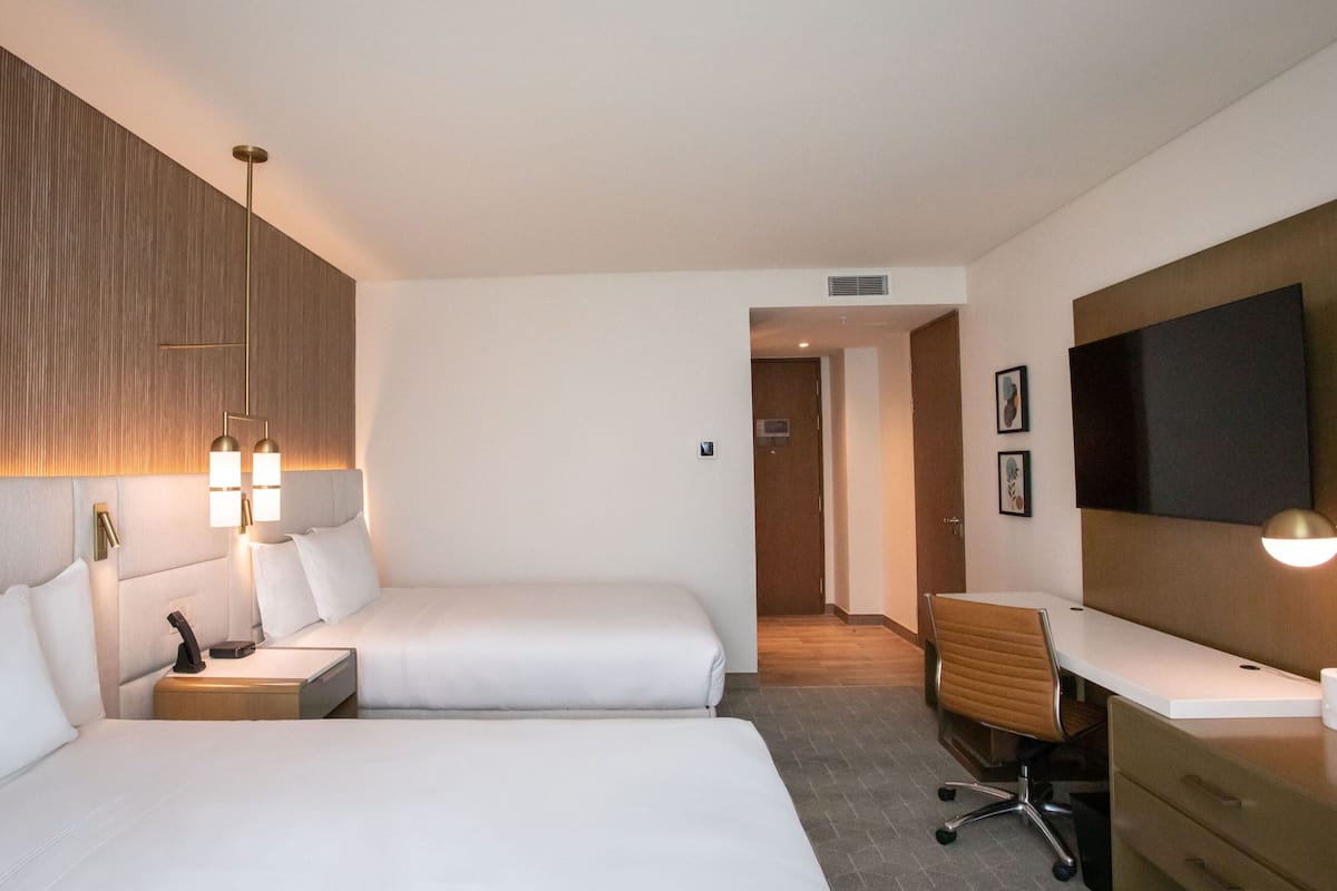 Habitació d'hotel amb dos llits, un escriptori i una televisió.