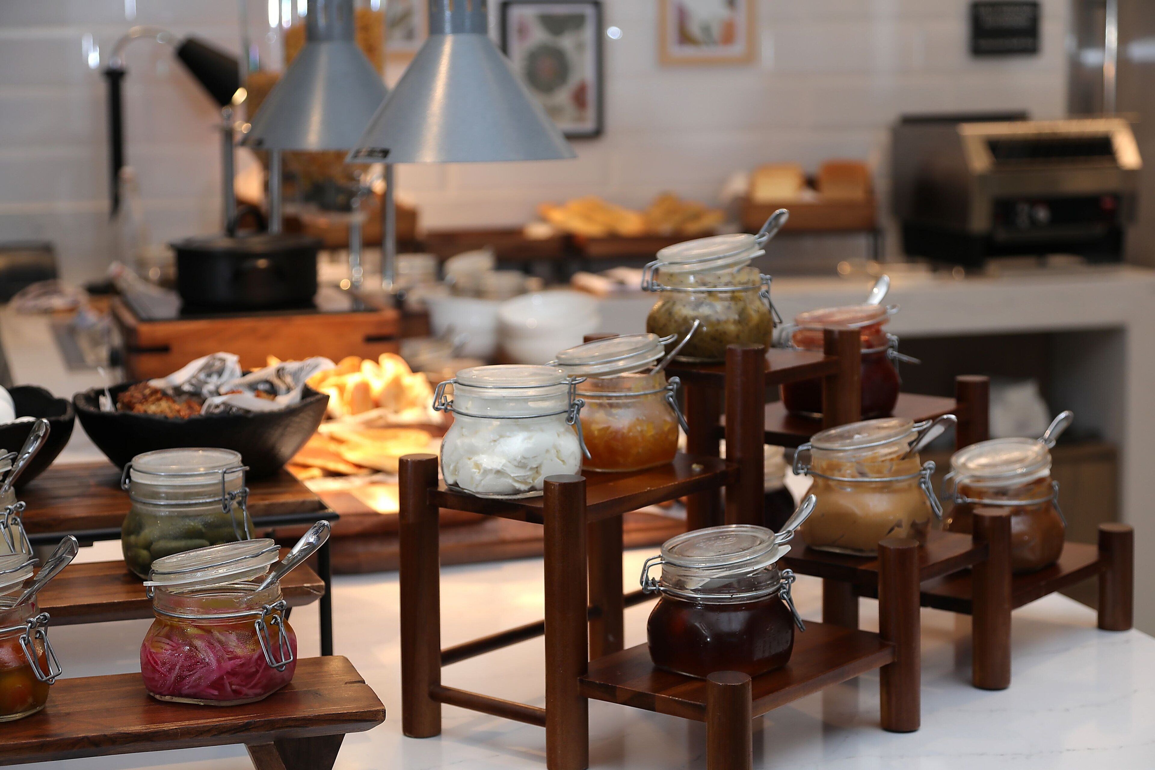A buffet setup with various food items in jars and bowls.