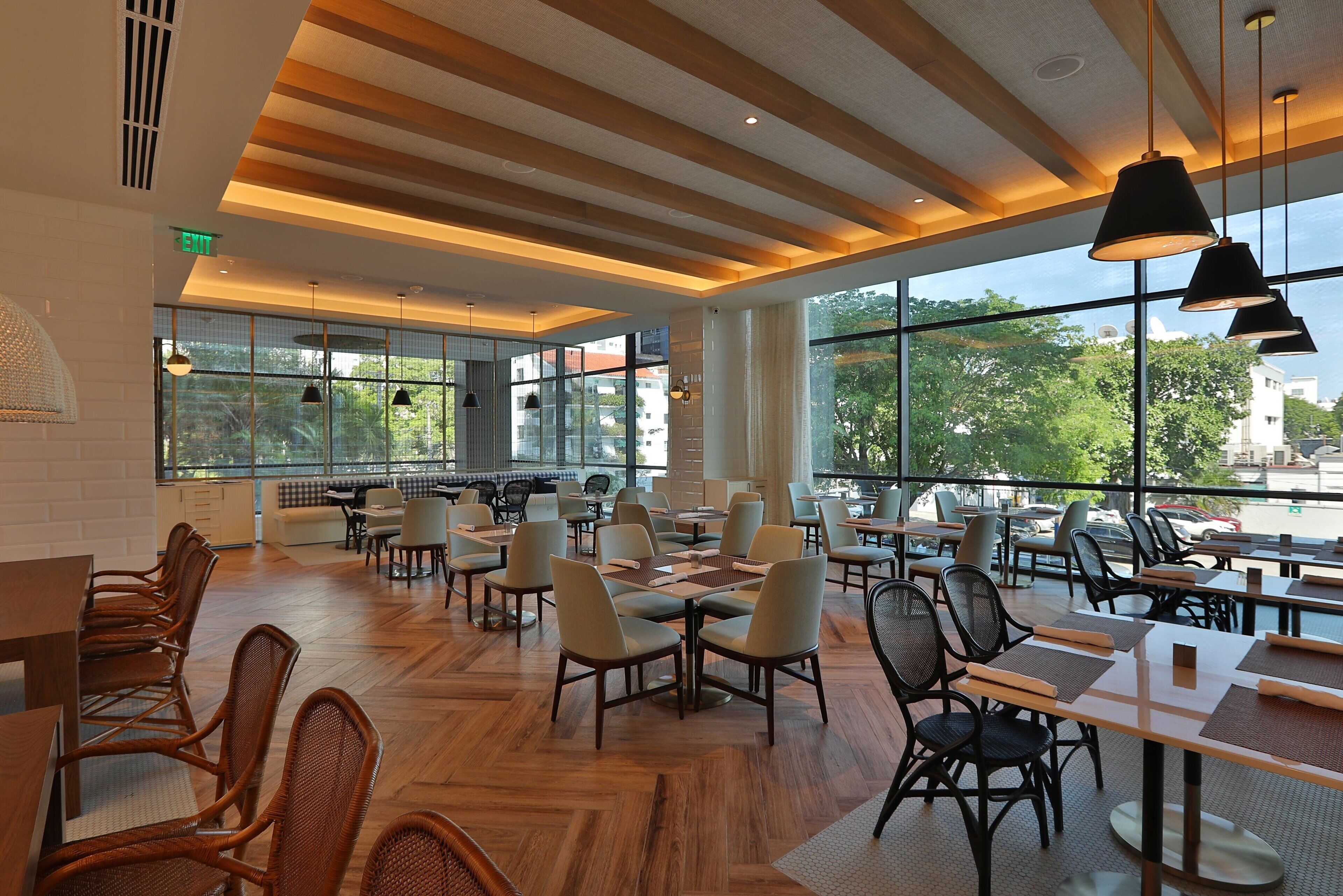 Un vaste espace de restauration intérieur, doté de hauts plafonds, de grandes fenêtres et de mobilier moderne.